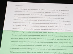 Green Irlen Overlay covering half of a paper with text. 