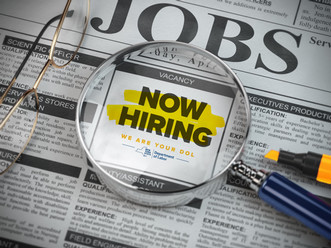 A job listing in a newspaper saying now hiring.