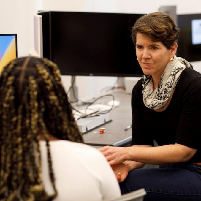 Professor Jenny Moore speaking with a faculty member.