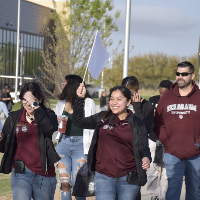 Two tour guides smiling and guiding a family through a campus tour