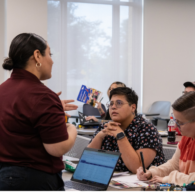 Two university workers helping students in a classroom setting 